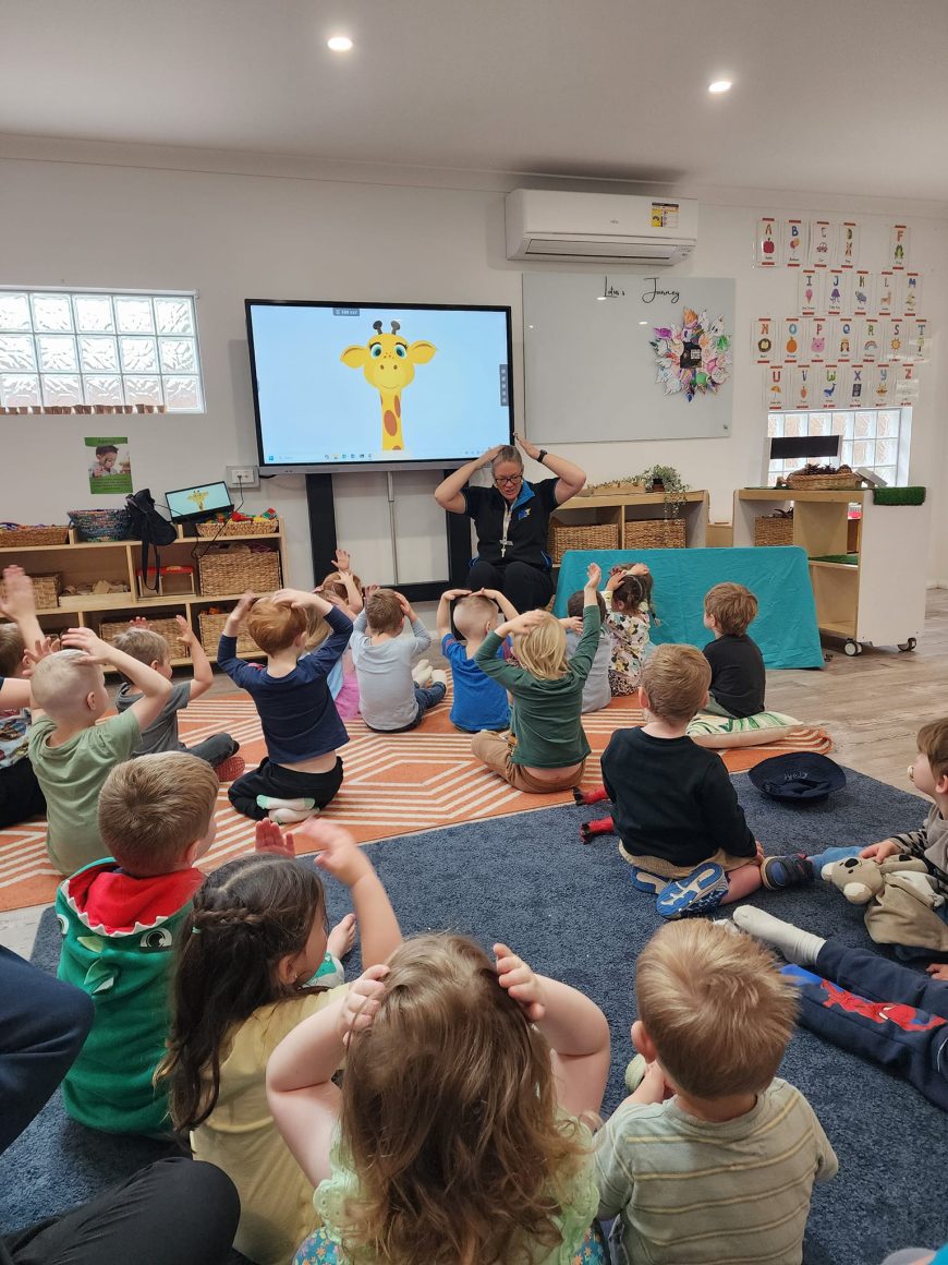 Children playing with their hands on their heads at our Eglinton childcare centre
