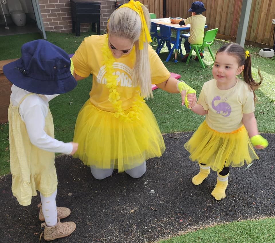 One of our educators and two children playing outside in Eglinton