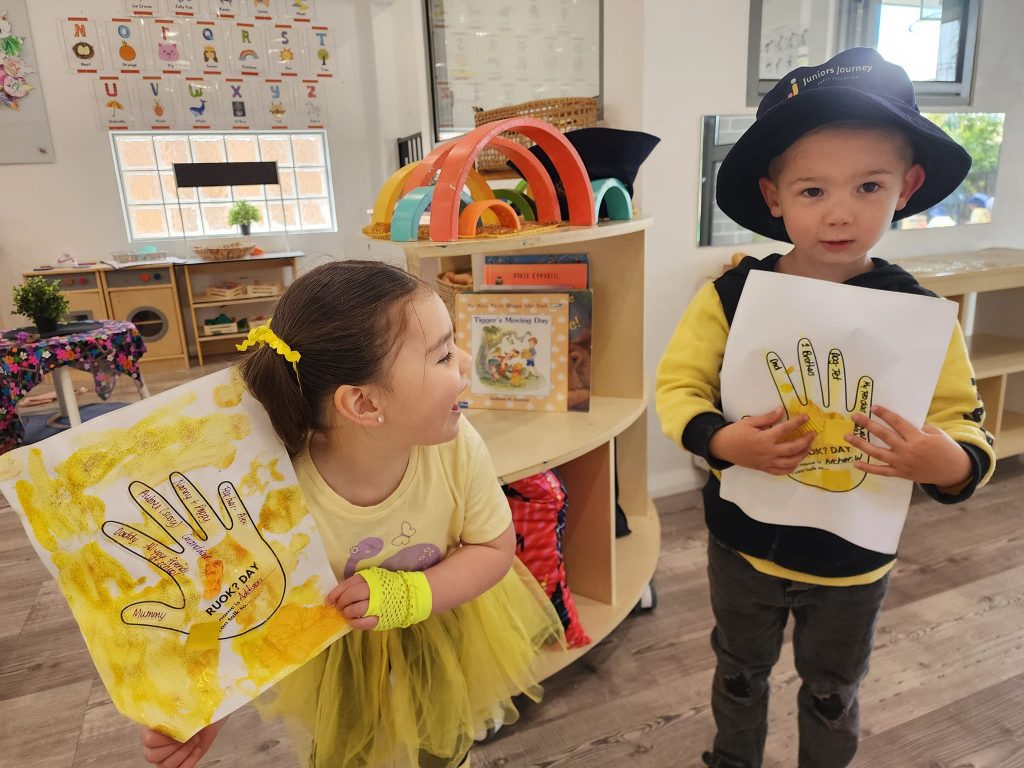 A boy and girl showing their drawings at our Eglinton childcare centre