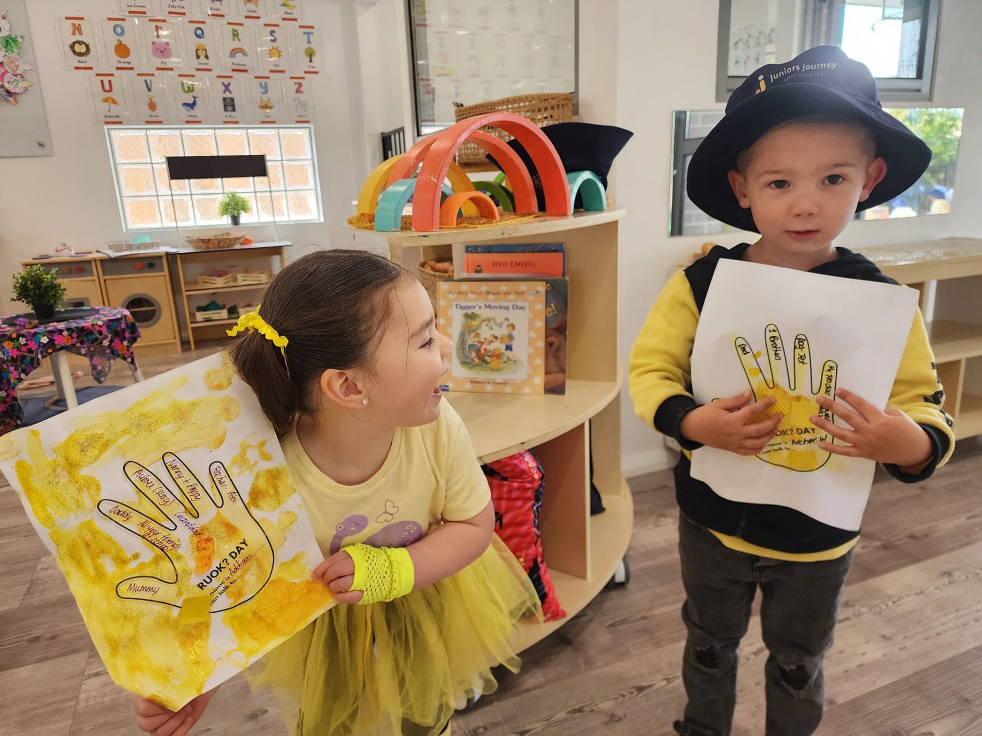 A boy and girl showing their drawings at our Eglinton childcare centre